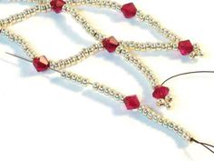 beaded necklace with red beads and silver findings on white background, close up view