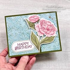 a hand holding a card with flowers on it and the words happy birthday written in white