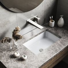 a bathroom sink sitting under a mirror next to a vase