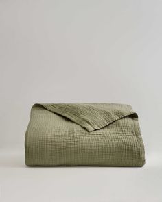 an olive green linen bed spread on a white background