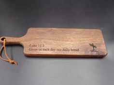 a wooden cutting board with the words luke 11 13 and an arrow on it, sitting on a table