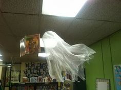 an office decorated for halloween with ghost decorations and bookshelves in the background,