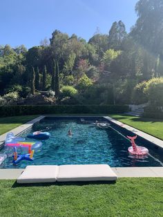 an inflatable pool with people swimming and floating on the water, surrounded by lush greenery