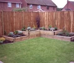 a backyard garden with wooden fence and green grass