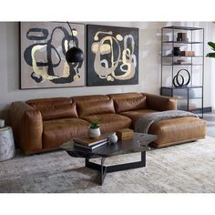 a living room with two paintings on the wall and a leather couch in front of it