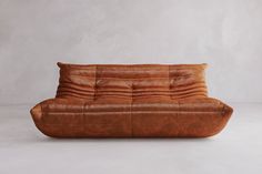 a brown leather couch sitting on top of a white floor next to a gray wall