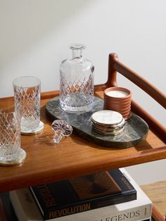 a wooden table topped with two glasses and plates on top of it next to books