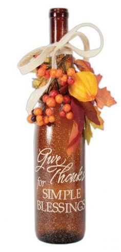 a bottle filled with lots of autumn leaves and berries on top of a white background