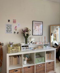 a white shelf filled with lots of books and baskets next to a wall covered in pictures