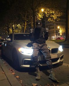 a man sitting on the hood of a car in front of a building at night