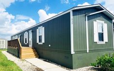 a green mobile home sits in the grass