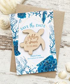 a save the date card with a wooden turtle on it and blue corals around it