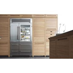 a stainless steel refrigerator in a kitchen next to wooden cabinets and counter top with wine glasses on it