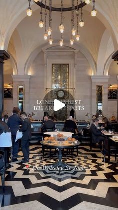 people sitting at tables in the lobby of a building with chandeliers hanging from the ceiling