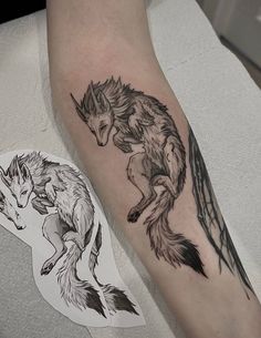 a black and white tattoo of two wolfs on the arm, one with its tail curled up