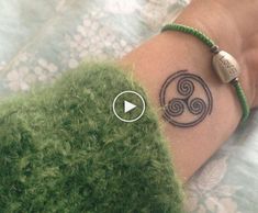 a woman's arm with a tattoo on it that has an image of a spiral design