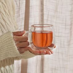 a woman holding a cup of tea in her hands