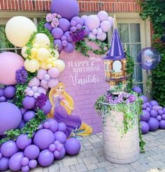 a birthday party with balloons and decorations on the side of a brick wall in front of a building