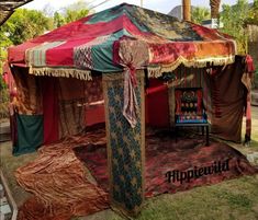 a tent that is sitting in the grass with some fabric on it's sides