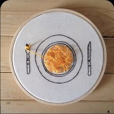 an embroidered plate with a fork and knife on it, next to a piece of orange peel