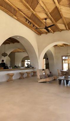 an open living area with chairs and tables in the center, surrounded by arched wooden ceilinging