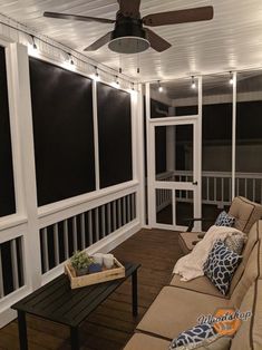 a screened porch with couches, table and ceiling fan on the back deck area