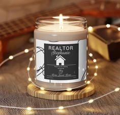 a lit candle sitting on top of a wooden table next to a string of lights