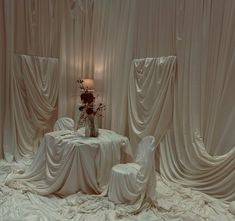 a table and chairs covered in white cloths with a vase on top of it