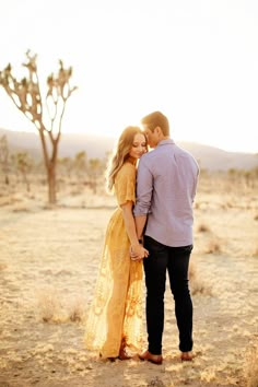 a man and woman kissing in the desert with trees in the backgrouds