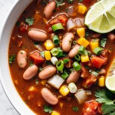 a white bowl filled with beans, corn and avocado on top of a table