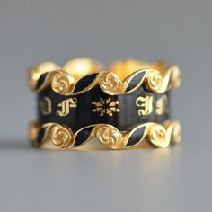 A fantastic antique Victorian Era (1837-1901) wide mourning band ring with black enamel in 18k yellow gold. An extremely crisp and in excellent condition striking wide early Victorian period mourning ring with the central panel featuring classic gold gothic letting "IN MEMORY OF" and flooded with glossy black enamel, the top and bottom features swirling cartouches with black enamel and gold roses or flowers. The interior of the band is hand engraved with "Tho's Latham died 3rd March 1843 Aet 46" Luxury Antique Engraved Ceremonial Ring, Luxury Victorian Men's Ring With Polished Finish, Luxury Victorian Jewelry With Decorative Band, Antique Black Enamel Rings, Antique Yellow Gold Signet Ring With Black Enamel, Elegant Black Hallmarked Enamel Ring, Black Enamel Wedding Jewelry, Black Enamel Jewelry For Wedding, Black Victorian Ring With Black Enamel