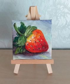 a painting of a strawberry on an easel