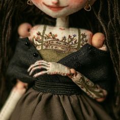 a doll with long hair and makeup is holding a black cloth bag in her hands