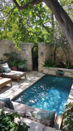 an outdoor swimming pool with lounge chairs around it and trees in the backround