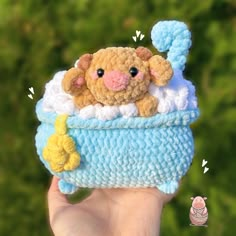 a hand holding a small stuffed animal in a crocheted basket