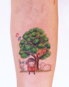 a woman with a book under a tree tattoo on her left leg, and two sheep in the background