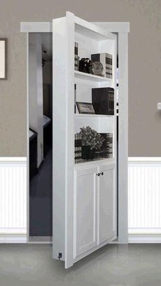 an open door leading into a kitchen with white cupboards and shelves on the wall