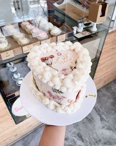 a person holding a cake in front of a display case