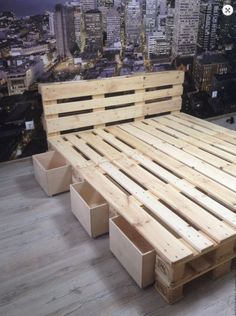 a bed made out of wooden pallets on top of a hard wood floor in front of a cityscape