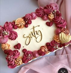 a birthday cake with pink and orange flowers on it that says sastg in gold lettering