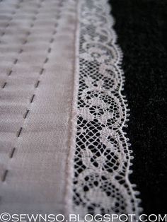 closeup of white lace on black fabric with stitching in the center and bottom