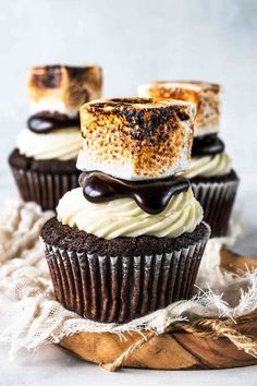 three cupcakes with chocolate frosting and marshmallows on top