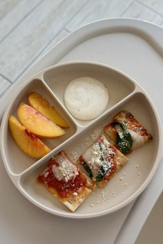 a white plate topped with slices of pizza next to peaches and yogurt