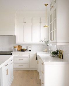 a kitchen with white cabinets and wood floors is seen in this image from the front view