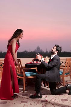 a man in a suit and tie sitting at a table with a woman wearing a red dress