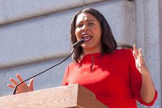 a woman in a red dress speaking at a podium