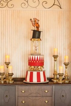 a red and white striped cake sitting on top of a wooden table next to candles