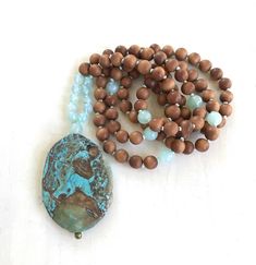 "Tranquility Mala Beads - Ocean Jasper & Sandalwood Beads - Hand Knotted - 108 Bead Mala - Length approx. 40\" The rhythmic cadence of the sea has always called humanity to its shores. This Ocean Jasper and Sandalwood Mala bead necklace from True Nature Jewelry brings that same spirit of peace and letting go. Hand knotted for flexibility and beauty, it features soothing and fragrant Sandalwood beads and Light Aqua Agate to help balance the emotions. A large Ocean Jasper pendant which brings Turquoise Spiritual Beads For Meditation, Spiritual Turquoise Beads For Meditation, Spiritual Beaded Necklaces With Oval Beads For Beach, Nature-inspired Beaded Necklaces With Natural Stones, Nature-inspired Beaded Necklaces With Round Natural Stones, Artisan Wooden Beads For Meditation, Artisan Wooden Meditation Beads, Holistic Handmade Beads For Meditation, Hand-strung Nature-inspired Beaded Necklaces