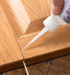 someone is using glue on wood to finish the edge of a piece of wooden floor