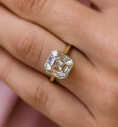 a close up of a person's hand with a diamond ring on their finger